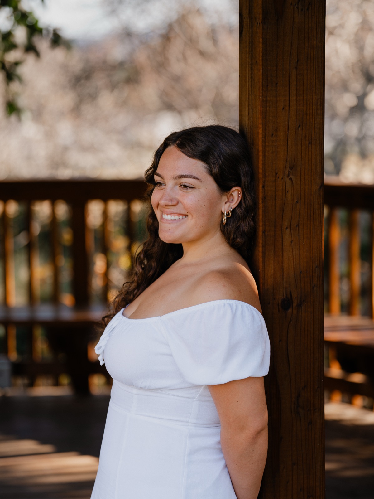 Senior girl in a white dress smiling against a wooden post, Arroyo Grande California