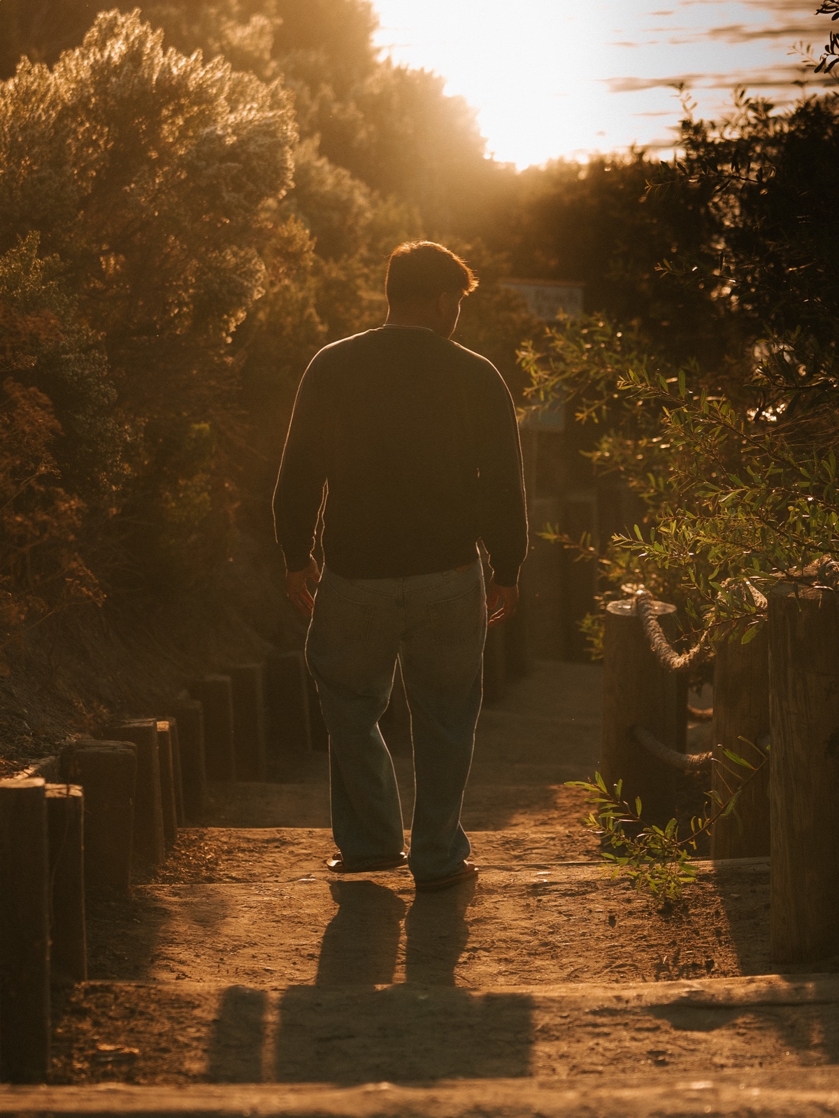 Senior silhouetted walking down a coastal path into golden hour sun — Central Coast senior photographer