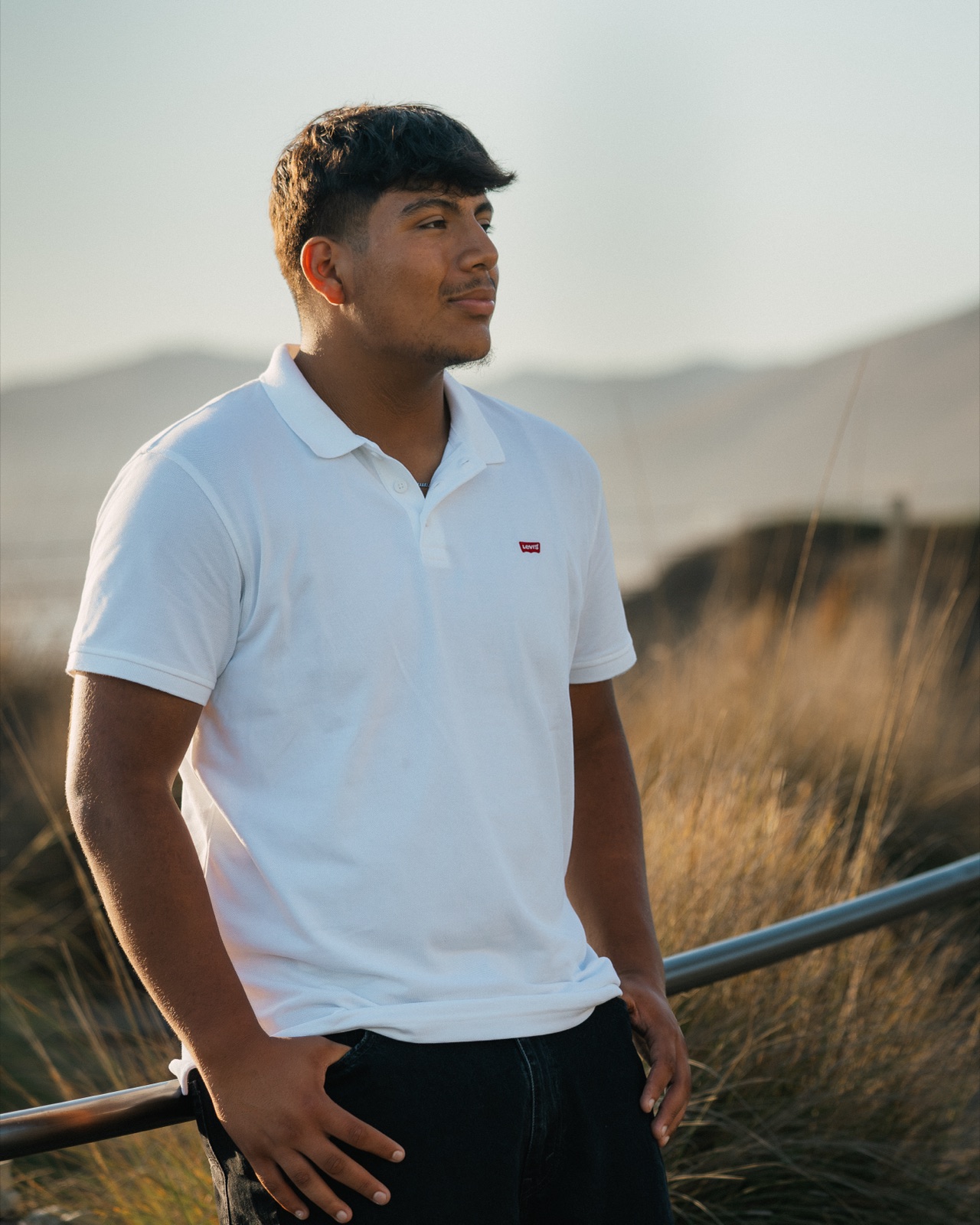 Senior in a white polo gazing out over golden coastal hills — Central Coast senior photographer